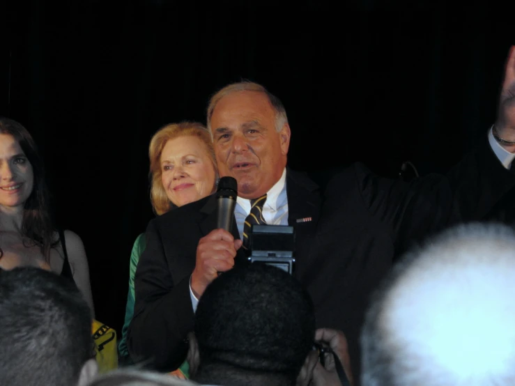 two men and one woman talking in front of a microphone