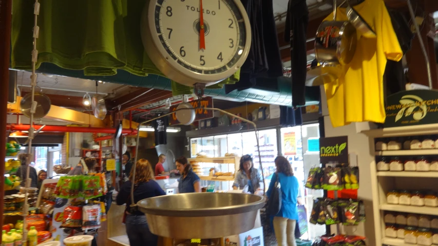 a group of people inside a shop with two large clocks