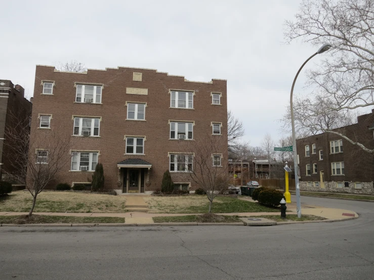 a large brick apartment building with windows and a green street sign