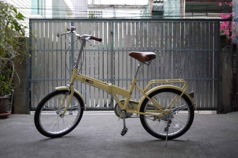 a yellow bike is standing near a fence