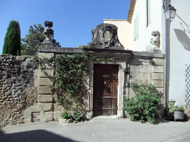 an old building that has a stone door and some plants growing all around it