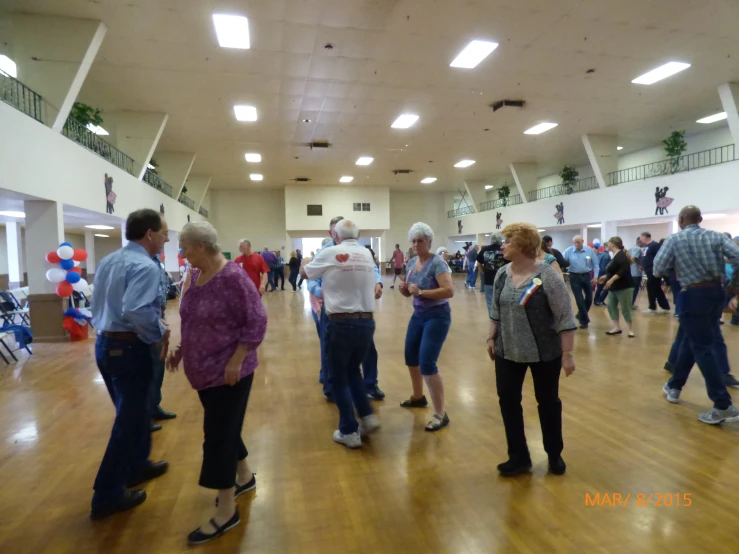 group of people dancing in a hall at a party