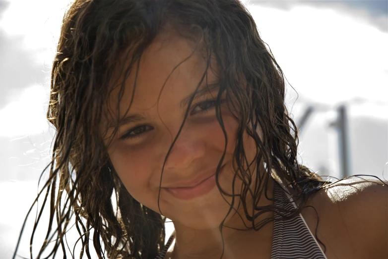a young lady is smiling with her wet hair blowing in the wind