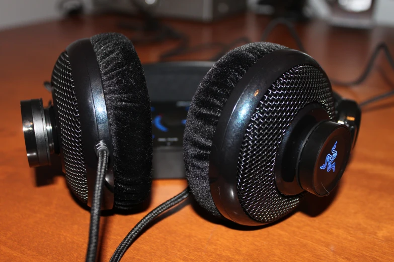 a pair of black headphones sitting on top of a wooden table