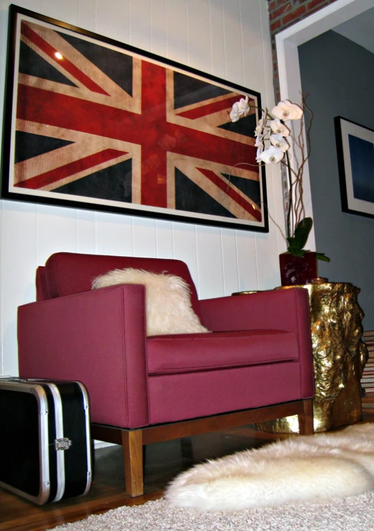 a red chair sitting next to a painting of the british flag