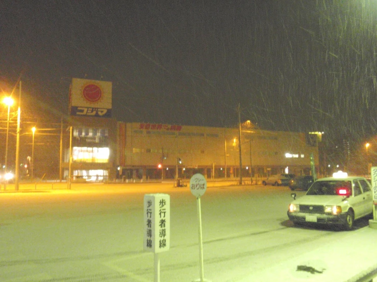 a car driving past a shopping center with street lamps