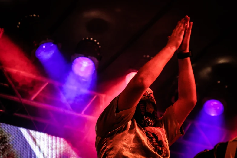 a person raising their hand with two hands in the air on a stage
