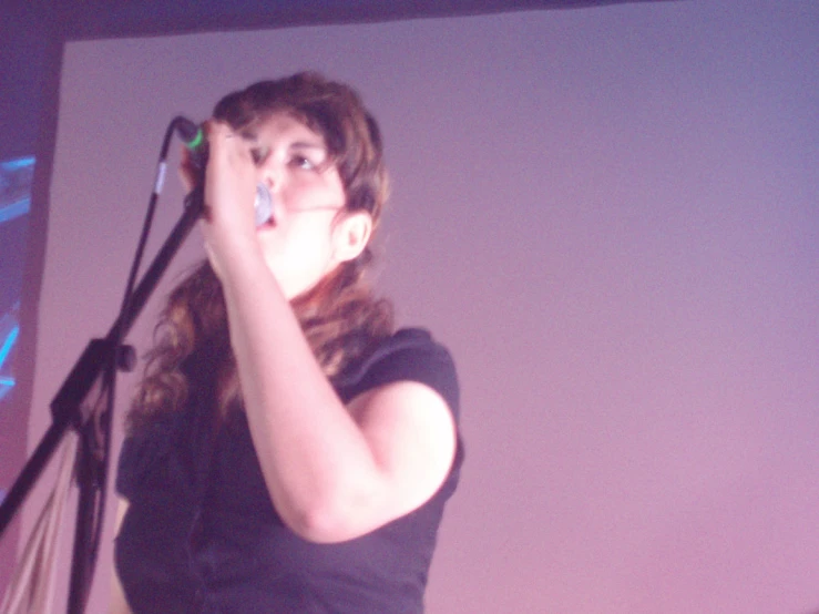 a woman singing into microphones on stage