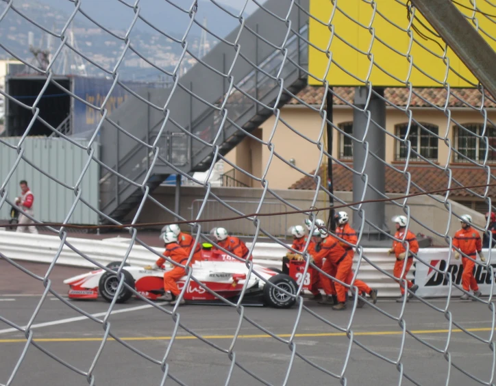 a group of mechanics in orange uniforms working on a race car