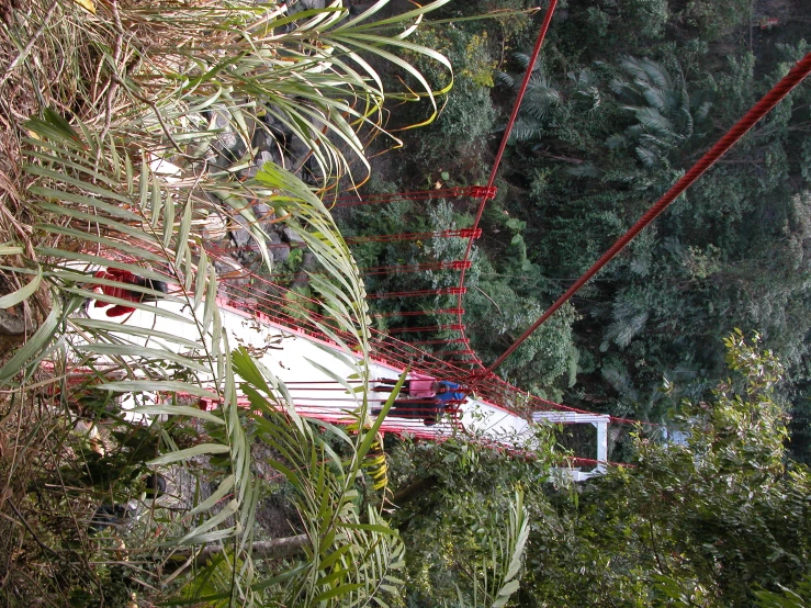 a suspension bridge going down a hill with a mountain in the distance