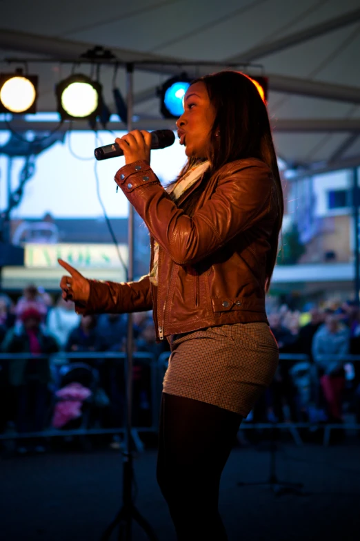 a woman holding a microphone in her right hand, as if singing