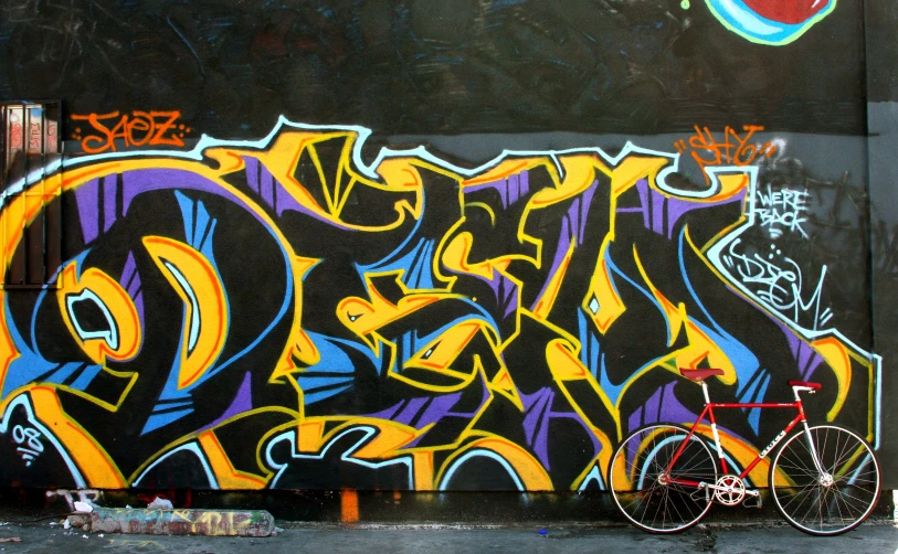 a bike parked in front of a wall with graffiti on it