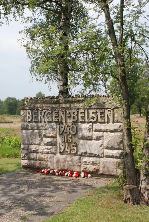 a memorial sign with flowers at the bottom of it