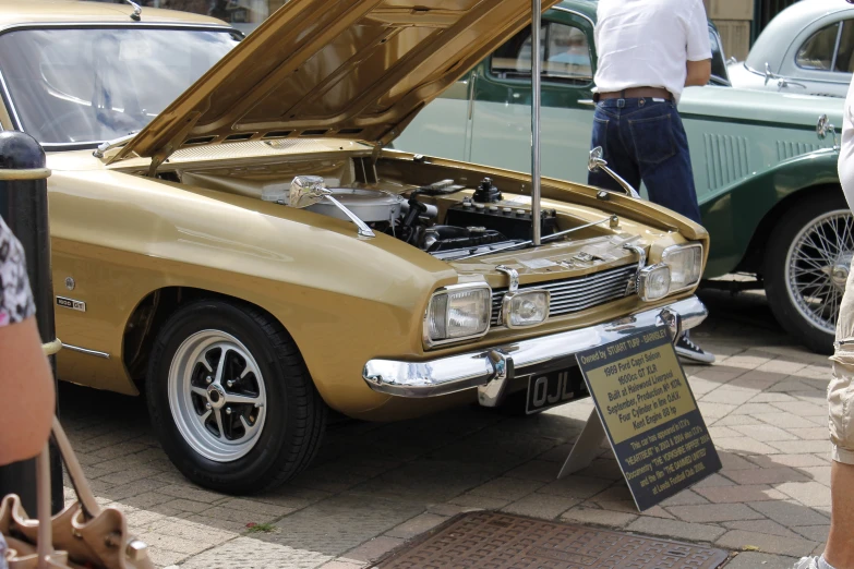 an old gold classic car with its hood up