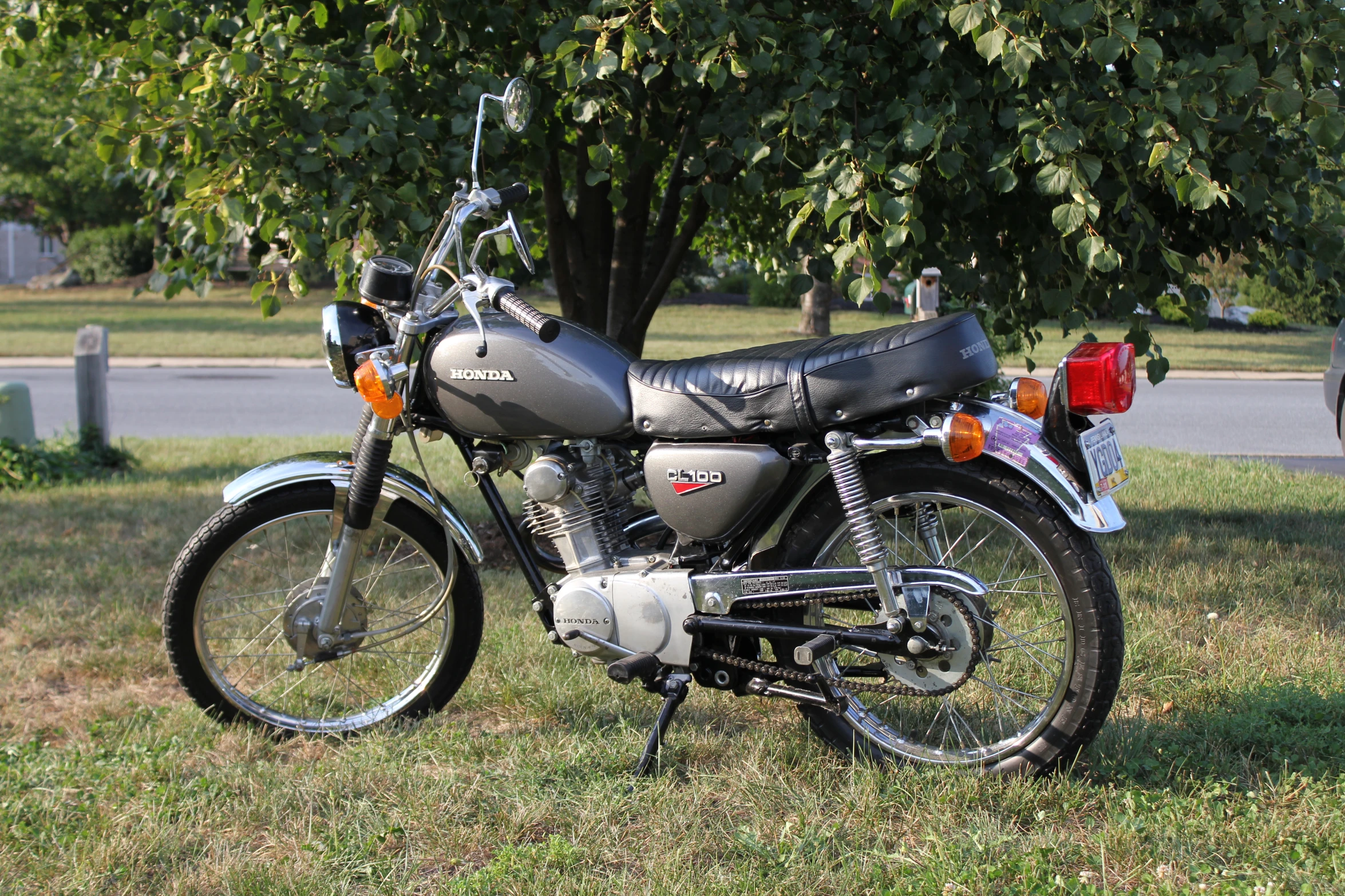 an old motorcycle is parked under a tree