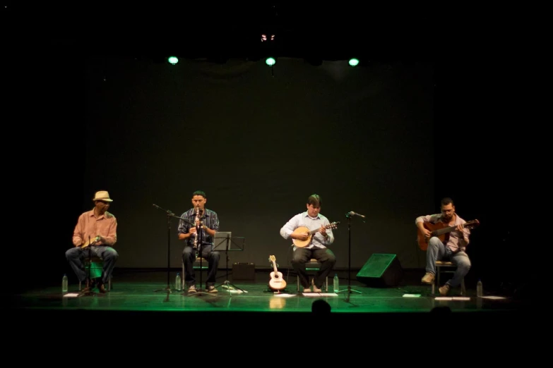 three men in concert on stage and one playing the guitar