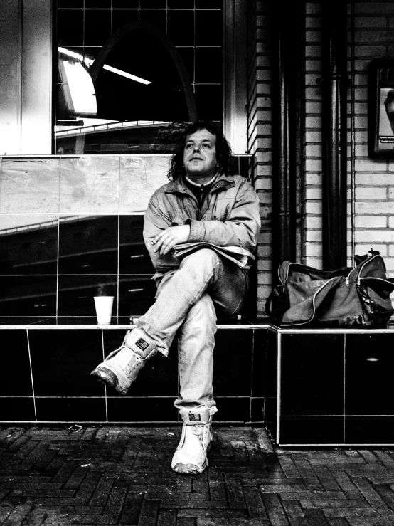 black and white image of a man sitting on a bench