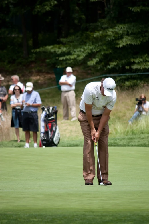 the golf player is bending down and waiting for his putt