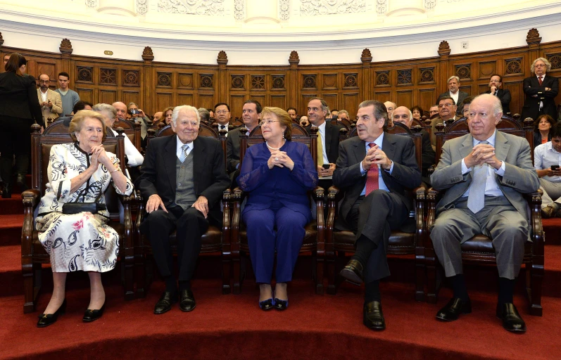 there are several people seated in chairs holding wine glasses