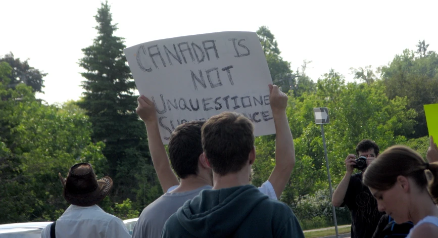 two men holding up a sign in front of other people