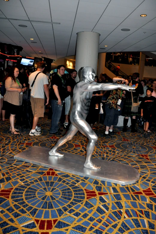 a statue in the middle of a lobby with people looking on