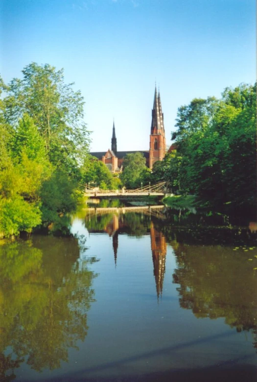 a small river runs past a gothic building on a bright day