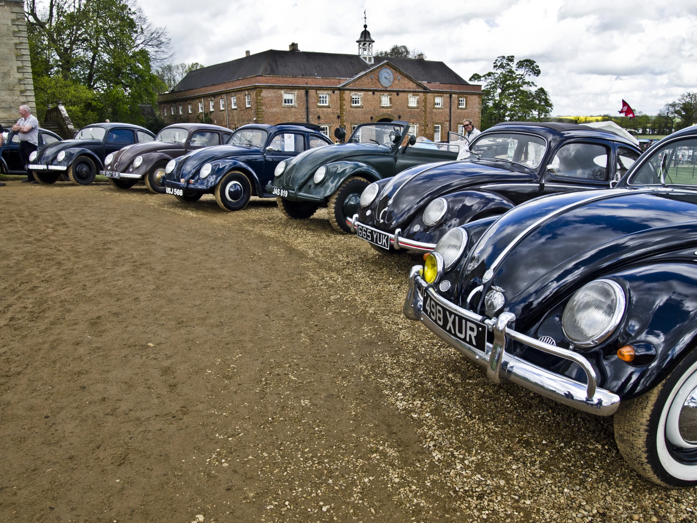 row of vintage cars parked in front of a large building