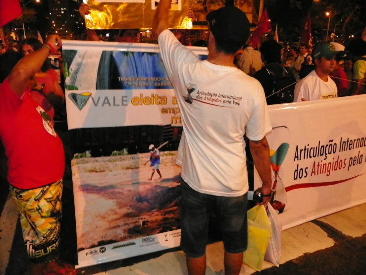 a man holding a surfboard while looking into a poster