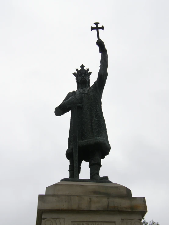 a statue is holding a cross up in the air