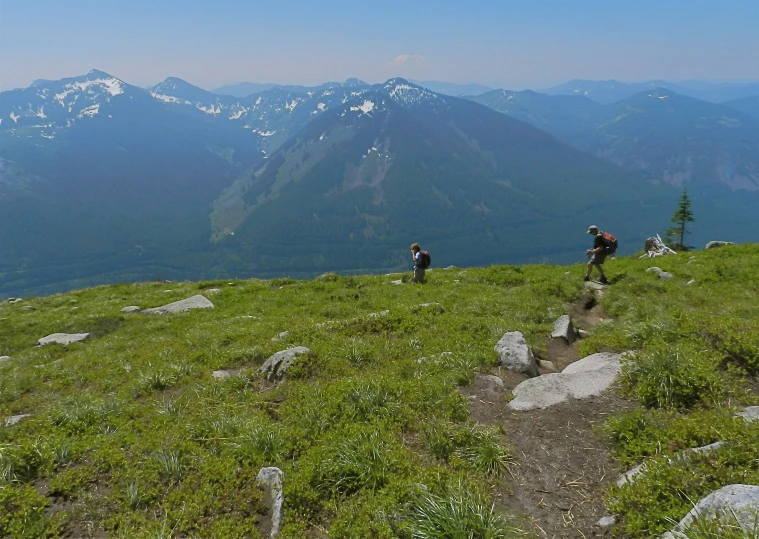 two men climb up a grassy hill to the top