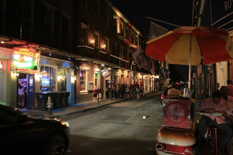 two people sit at an outside dining table under an umbrella on the sidewalk