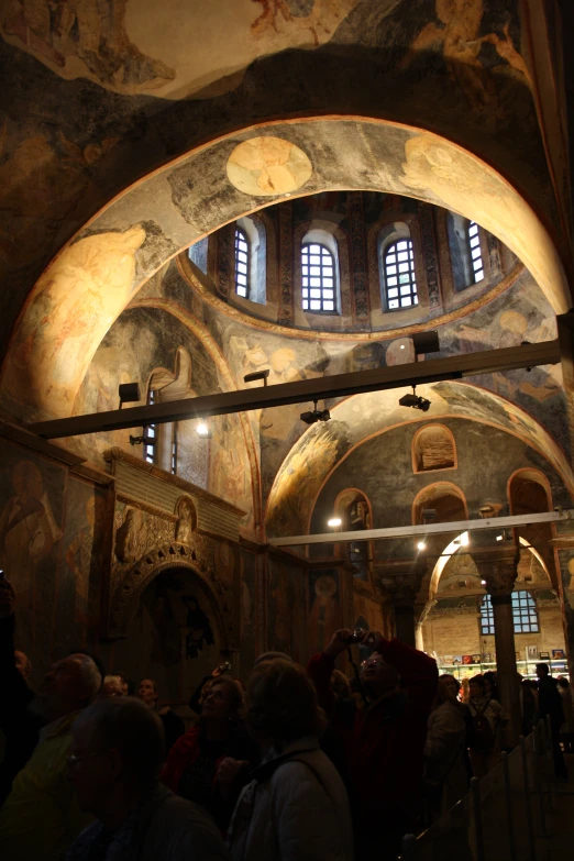 large crowd of people looking up at an ornately painted building