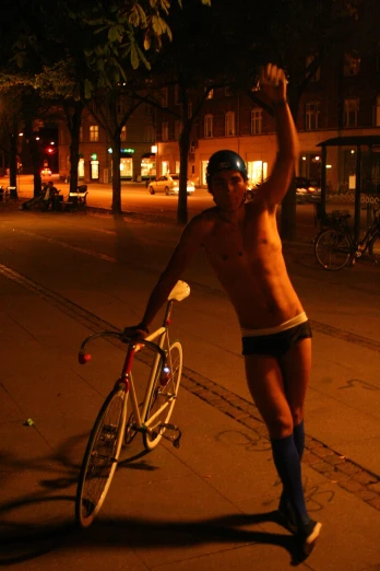 a man without a shirt holding a bicycle with his right arm