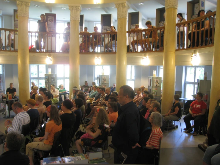 a large room with people standing and sitting