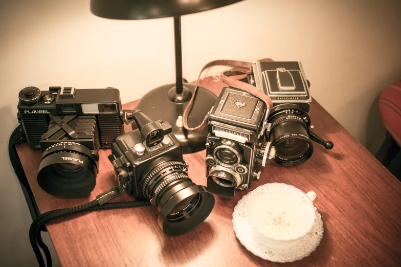 a table topped with two cameras and an older style flash camera