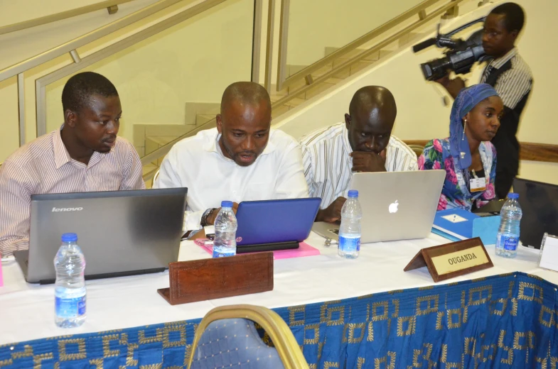 a group of people are on laptops at a table