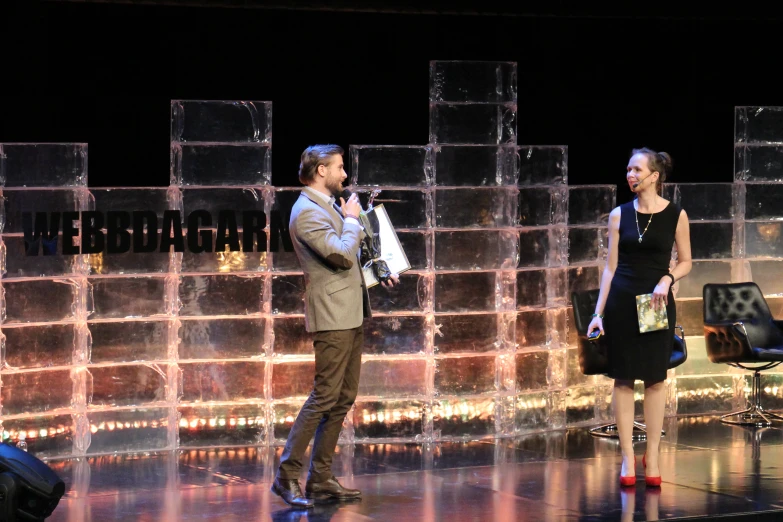 a man and woman talking while standing on a stage