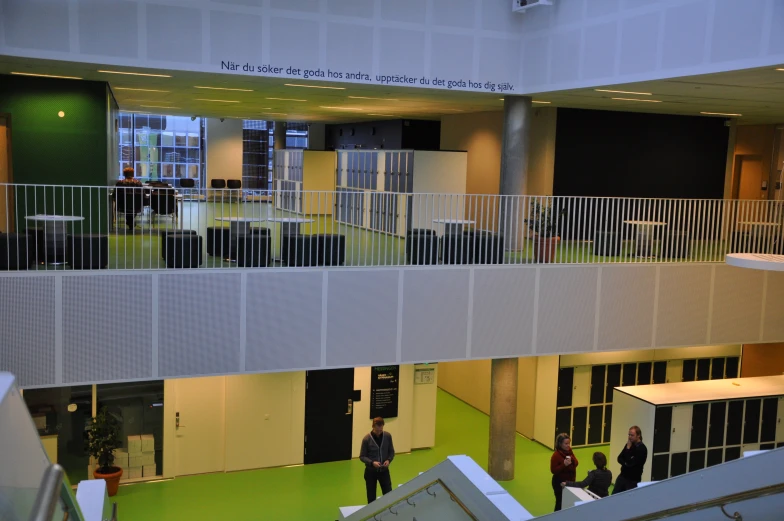 people walking through a building with stairs and a third story in the background