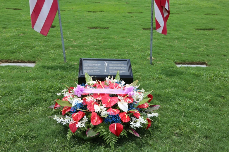 a floral wreath on the ground with two american flags