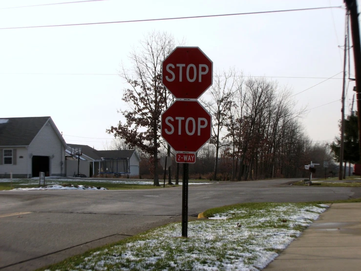 two stop signs sit next to each other in the snow