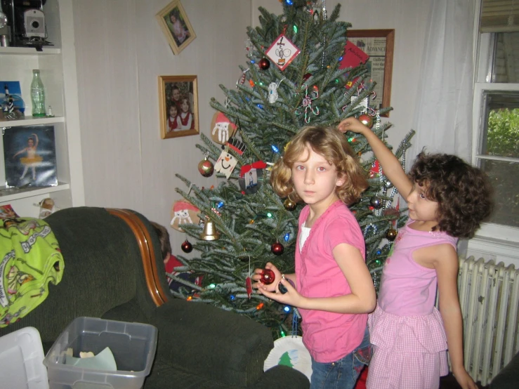 a small girl putting decorations on a christmas tree