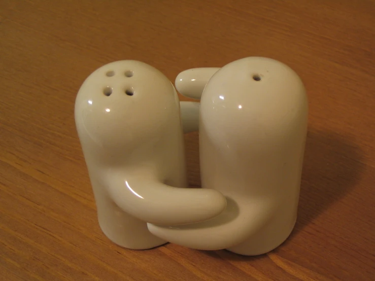 two white figurines sitting on top of a wooden table
