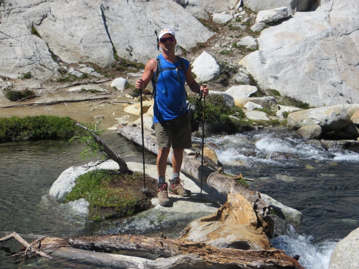 a man standing on some rocks with poles by a river