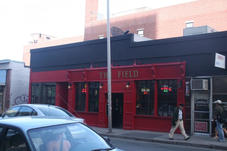 a man walking past red stores along a street