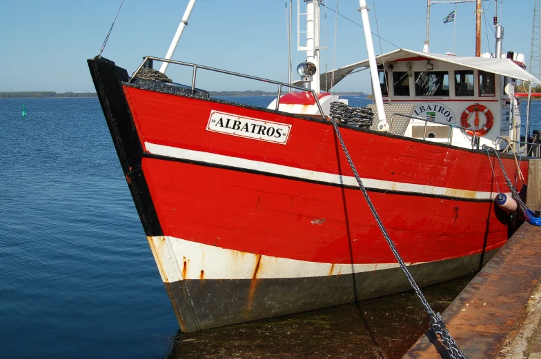 the large red and white boat is docked at the pier