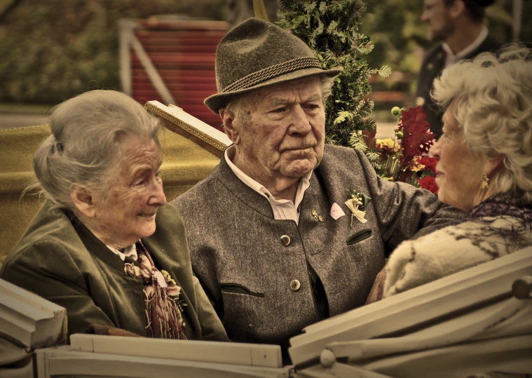 a man is sitting on an old fashioned couch while talking to some older people