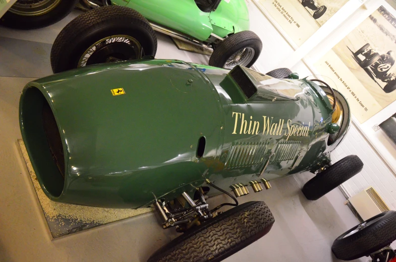 two antique race cars sit on display in a museum