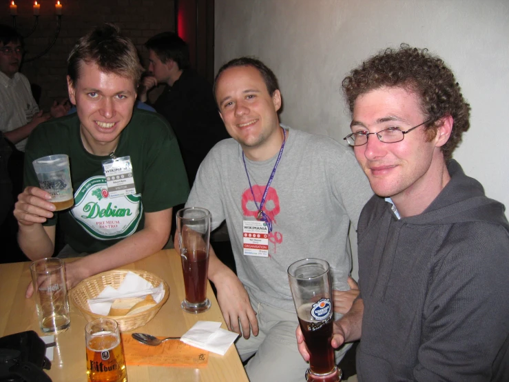 two guys sit down at a table with beers in their hand