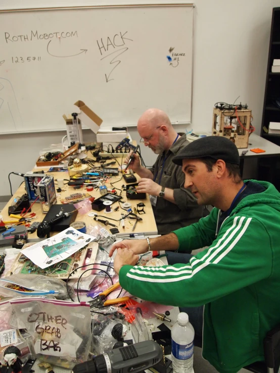 three men at a long table with electronics and electronics on the table