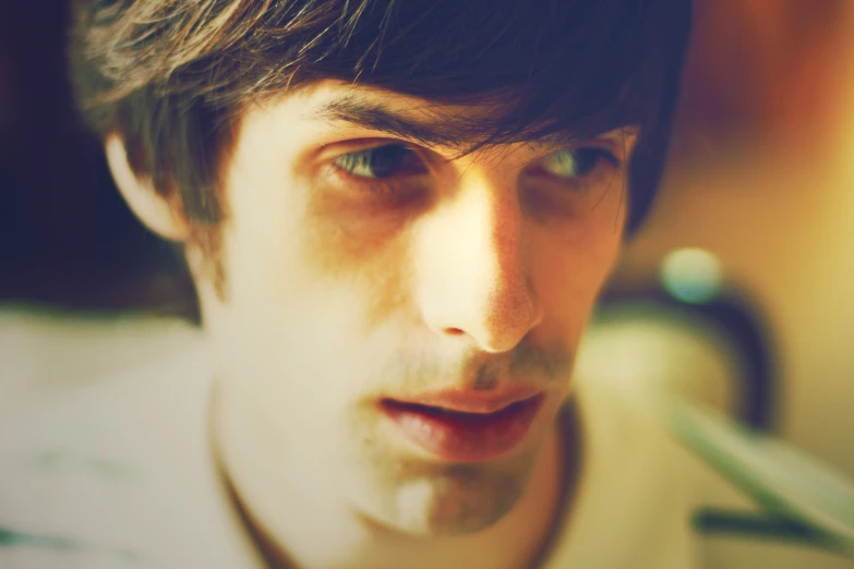 a man with short hair wearing a white shirt and looking intently into the camera